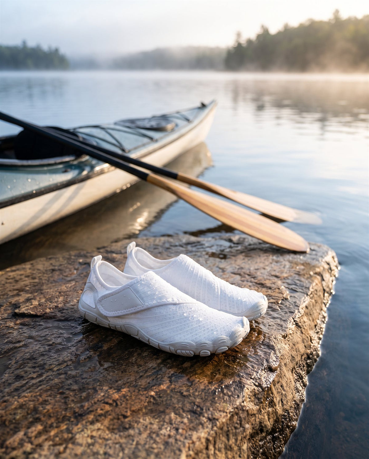 White Brizway shoes on a wet rock at a lake edge beside a kayak and paddle